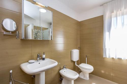 La salle de bains est pourvue d'un lavabo, de toilettes et d'un miroir. dans l'établissement Apartment VIVIANA, à Pula
