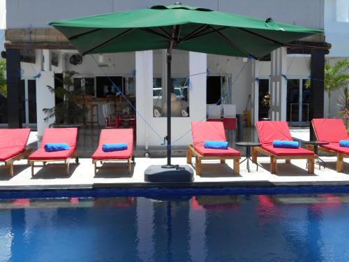 a group of chairs and an umbrella next to a pool at Silver Fern Beach Retreat in Sekotong