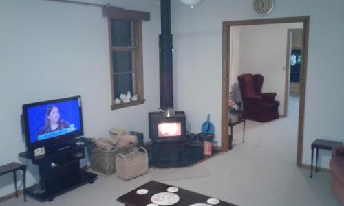ワンガヌイにあるThe_Cozy_Batch With a rural viewのリビングルーム(テレビ、コンロ付)