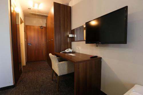 a hotel room with a desk with a television on the wall at Hotel Sliško in Zagreb