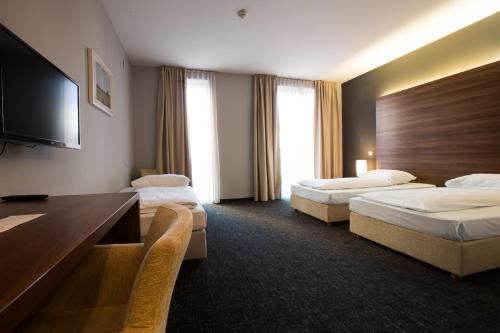 a hotel room with two beds and a flat screen tv at Hotel Sliško in Zagreb