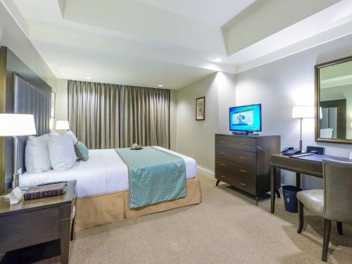 a hotel room with a bed and a desk and a television at Somerset Millennium Makati in Manila