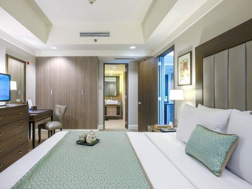a hotel room with a large bed and a desk at Somerset Millennium Makati in Manila