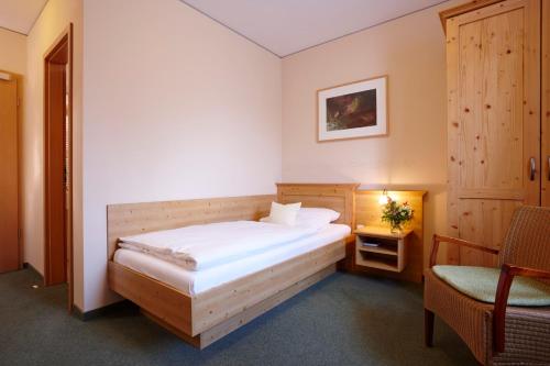 een slaapkamer met een bed, een tafel en een stoel bij Hotel Eberl in Hattenhofen