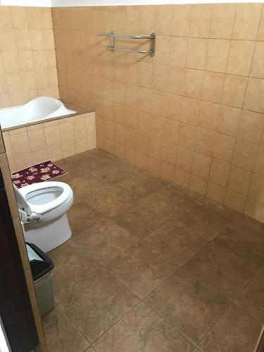 a bathroom with a toilet and a tiled floor at Santana Bali Home stay in Ubud