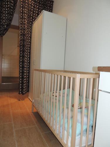 a crib in a room with a white refrigerator at Ferienwohnungen am Hauptplatz in Pirna