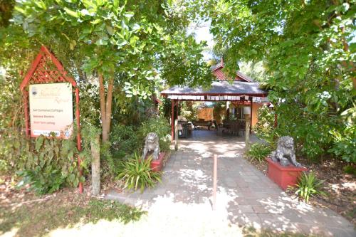 a garden with a pavilion with a table and a sign at Shambhala Retreat Magnetic Island Cottages in Nelly Bay