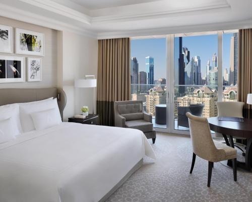 a bedroom with a bed and a desk and a large window at Kempinski The Boulevard Dubai in Dubai
