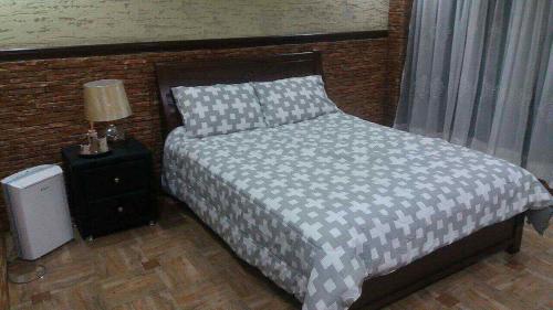 een slaapkamer met een bed en een nachtkastje met een lamp bij Affordable Baguio APT in Baguio
