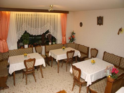 un restaurante con dos mesas y sillas con flores. en Landhaus Enztalperle, en Enzklösterle
