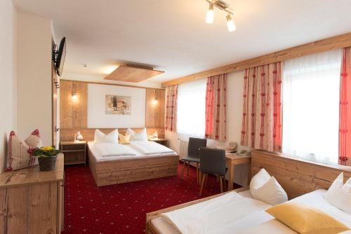 a hotel room with two beds and a desk at Pension Singer in Innsbruck