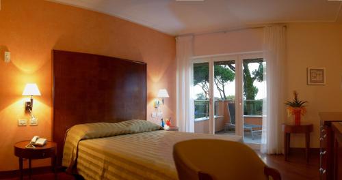 a bedroom with a bed and a large window at Versilia Palace Hotel in Marina di Pietrasanta