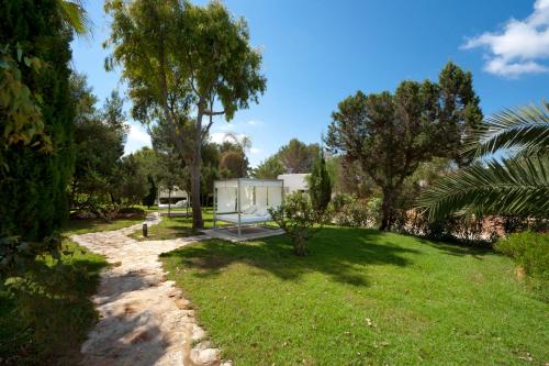 a garden with a house in the background at Villas Paraíso de los Pinos in Sant Francesc Xavier