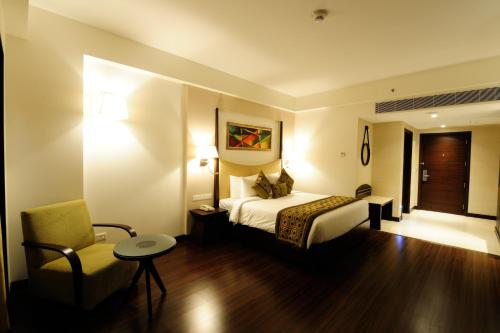 a hotel room with a bed and a chair at Gurmon Hotels Sohna Road Gurugram, a member of Radisson Individuals in Sohna