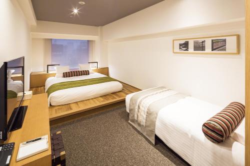 東京にあるホテルマイステイズプレミア大森のベッド2台とデスクが備わるホテルルームです。