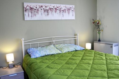 a bedroom with a bed with a green comforter at Kalimera Apartment in Nafplio