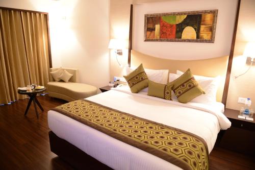 a hotel room with a large bed and a chair at Gurmon Hotels Sohna Road Gurugram, a member of Radisson Individuals in Sohna