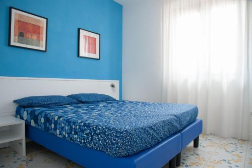 a blue bedroom with a bed and a blue wall at Settessenze Residence & Rooms in Agropoli