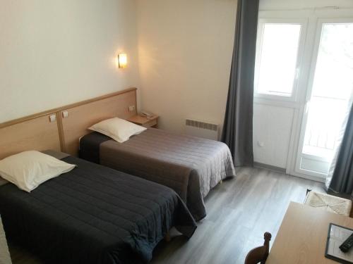 a hotel room with two beds and a table at Le Provence in Manosque