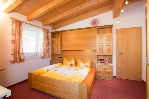 Schlafzimmer mit einem großen Bett mit einem Kopfteil aus Holz in der Unterkunft Haus Alois in Sölden