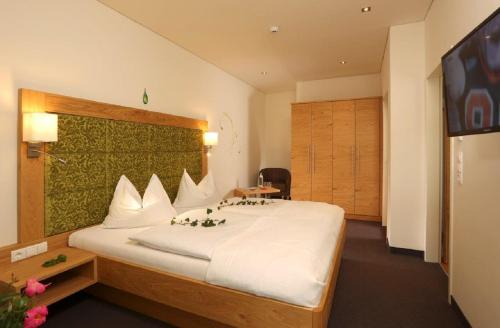 a bedroom with a large white bed and a television at Aparthotel Rubinius in Wagrain