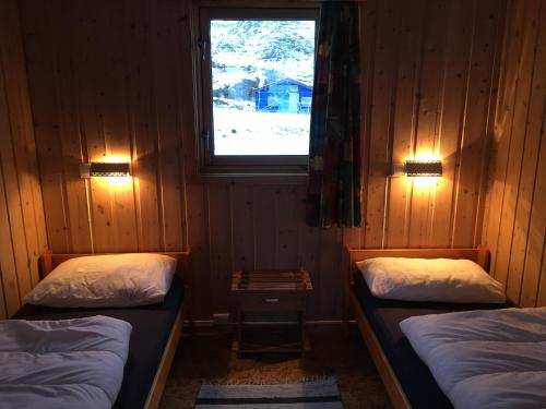 2 camas individuales en una habitación con ventana en Nordkapp Camping, en Honningsvåg