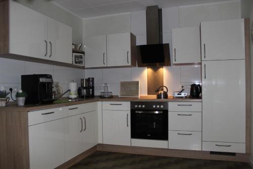 a kitchen with white cabinets and a black oven at Fewo An der Mühlenbachaue in Nettetal