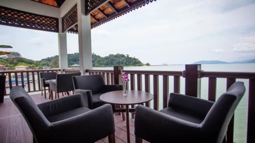 a balcony with chairs and a table and a view of the water at Casuarina Pangkor in Pangkor
