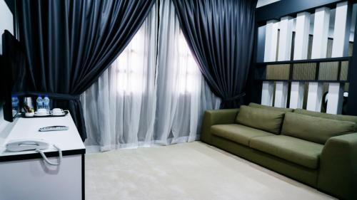 a living room with a green couch in front of a window at Casuarina Pangkor in Pangkor