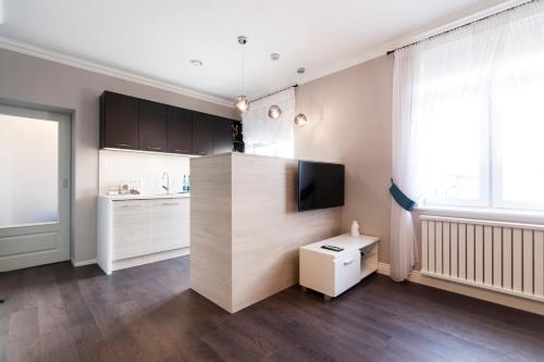 a kitchen with white cabinets and a flat screen tv at Apartamenty City. in Białystok