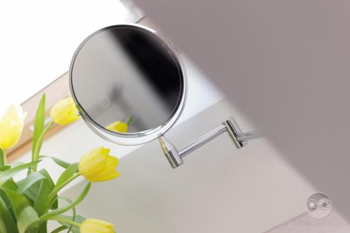 a mirror on a table with yellow flowers at Apartamenty City. in Białystok