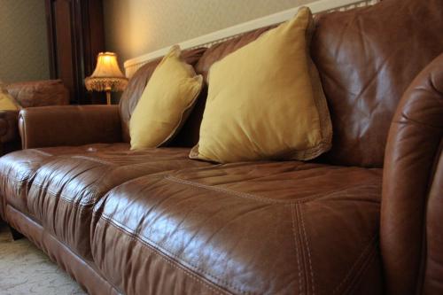 a brown leather couch with two pillows on it at The Limes in Stow on the Wold