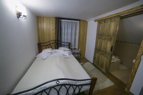 a bedroom with a bed with white sheets and a bathroom at Casa Verde in Voronet