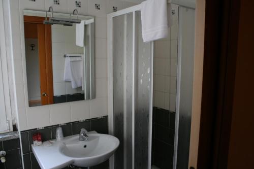a bathroom with a sink and a shower with a mirror at Hotel De La Ville in Bereguardo