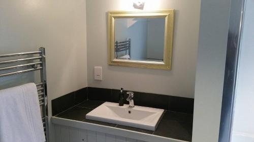 y baño con lavabo blanco y espejo. en The Mill House en Tintagel