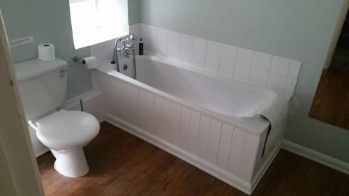 a bathroom with a white tub and a toilet at The Mill House in Tintagel