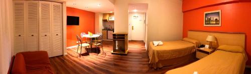 a bedroom with orange walls and a bed and a table at Intersur Suites in Buenos Aires
