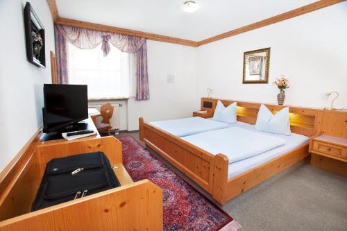a bedroom with two beds and a flat screen tv at Hotel Hubertus in Kissing