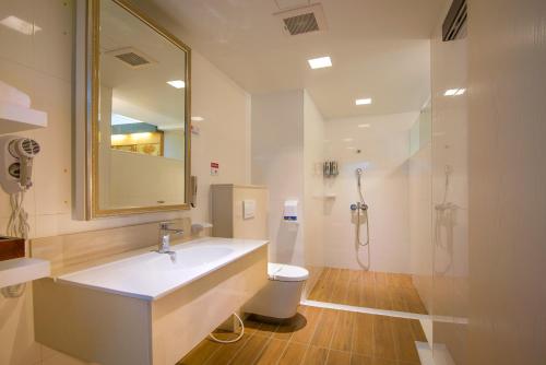 ein Badezimmer mit einem Waschbecken, einem WC und einem Spiegel in der Unterkunft M Garden Business Hotel in Tainan