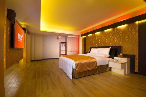 ein Hotelzimmer mit einem großen Bett und einem TV in der Unterkunft M Garden Business Hotel in Tainan