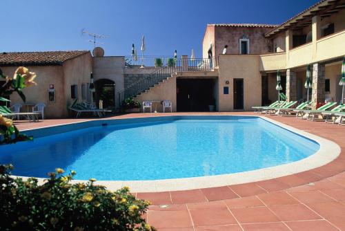 a swimming pool in a yard with chairs and a building at Hotel Villa Gemella in Baja Sardinia