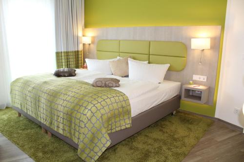 a bedroom with a large bed with a green headboard at Hotel Am Kaisersaal in Erfurt