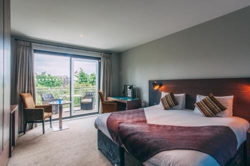 um quarto de hotel com uma cama e uma grande janela em The Cornwall Hotel Spa & Lodges em St Austell