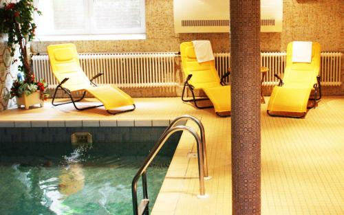 a pool with yellow lounge chairs and a swimming pool at Hotel König-Stuben in Bispingen