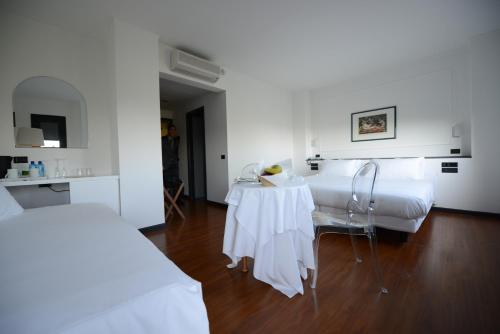 a white room with two beds and a table at Hotel Mamiani & Relaxing Spa Urbino in Urbino