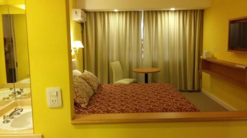 a hotel room with a bed and a mirror at Hotel Colonos in Las Grutas