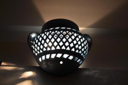 a black vase sitting on a table in the shadows at La Dimora dell' Architetto in Gravina in Puglia