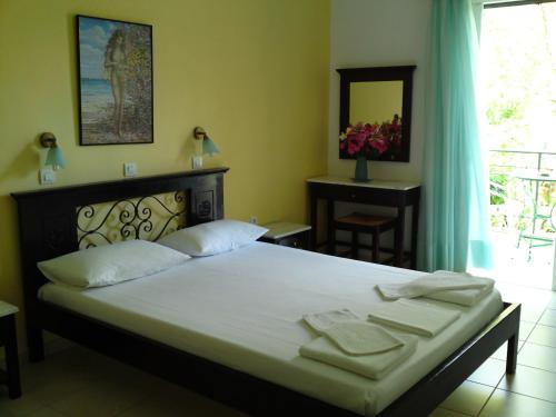 a bedroom with a bed with white sheets and a window at Sundy's Studios in Nydri