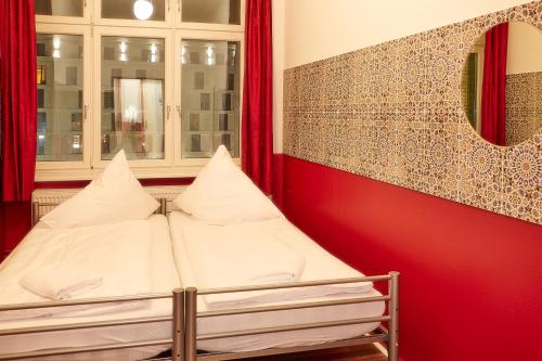 a bedroom with a bed with red walls and a window at Ballhaus Berlin Hostel in Berlin