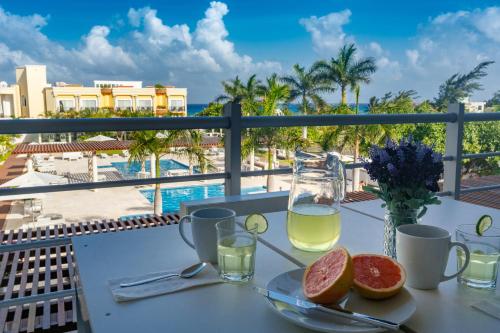 a table with a glass of wine and fruit on a balcony at Magia Beachside Condo in Playa del Carmen